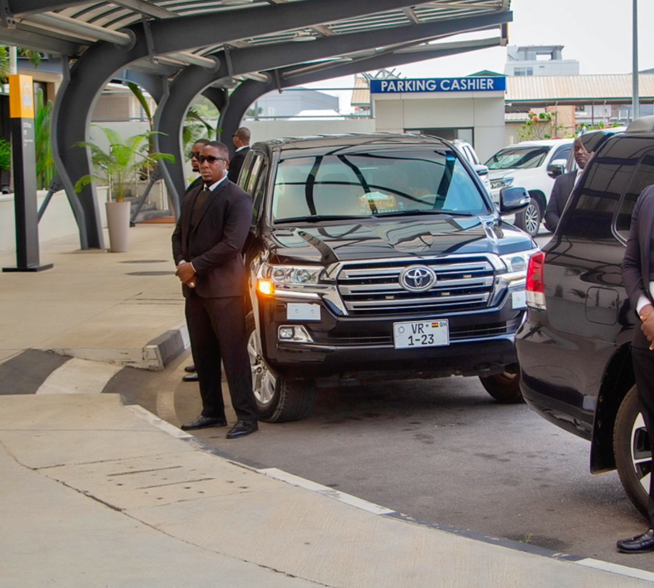 bodyguard in sunglasses opening car door to businessman